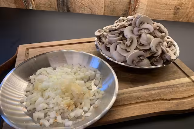 Champignoner i skiver. løg og hvidløg skæres i terninger.